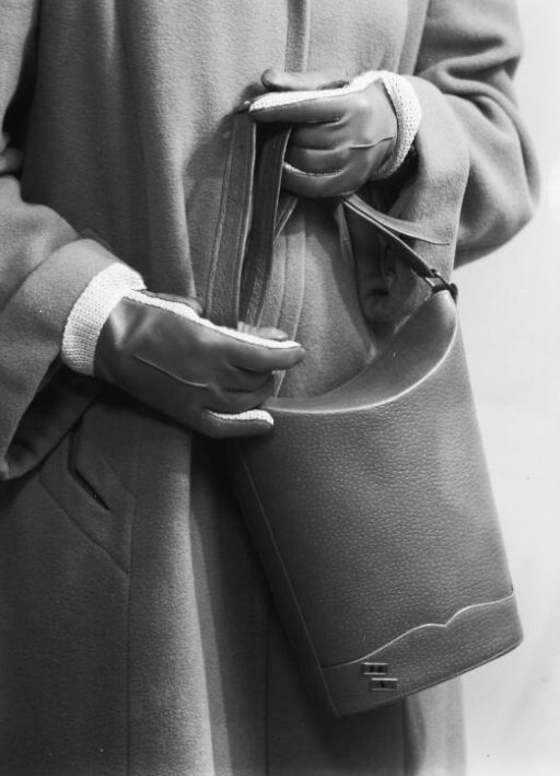 Gloved hands cradling a finished leather bag