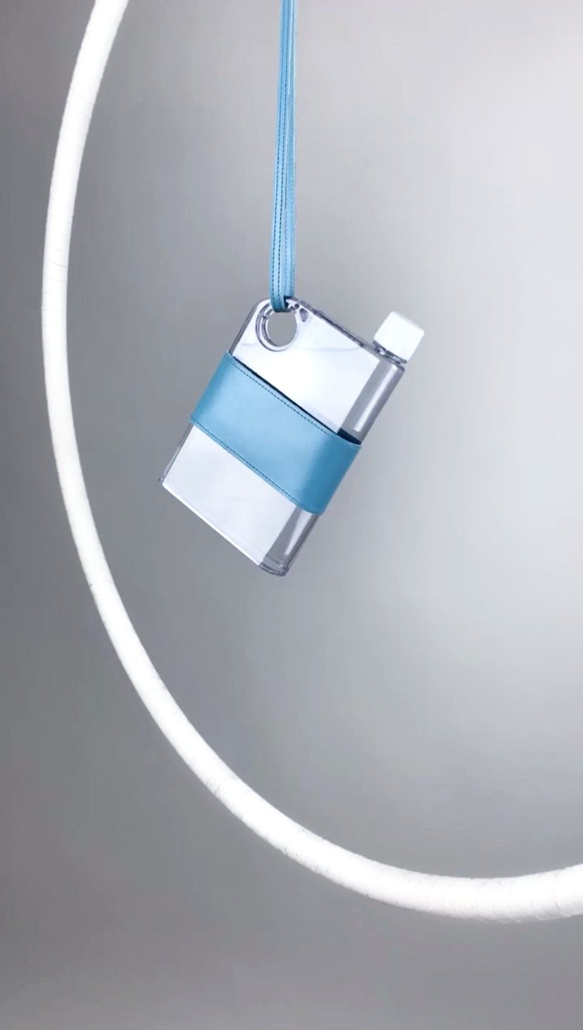 The Jugs, a flat clear water bottle in a pale-blue leather sleeve on a slim carry strap