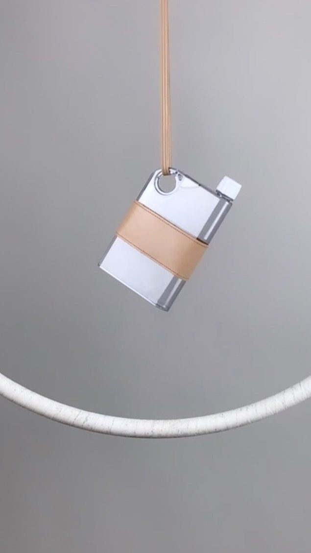 A flat Safiera water bottle in a leather sleeve, carried on a slim leather shoulder strap