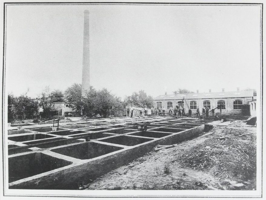 A historic Dutch leather tannery with open tanning pits and a tall brick chimney