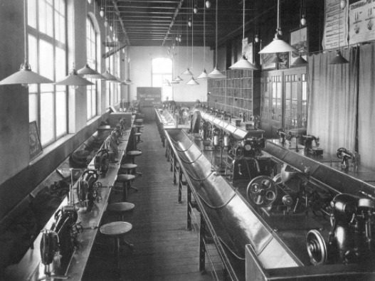 A long industrial hall lined with sewing machines for making leather goods